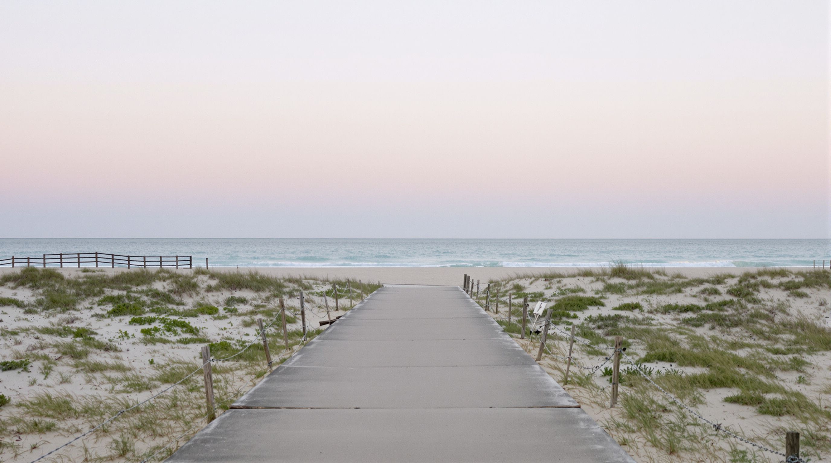 A walkway through sea oats and dune fencing to the Atlantic at dawn