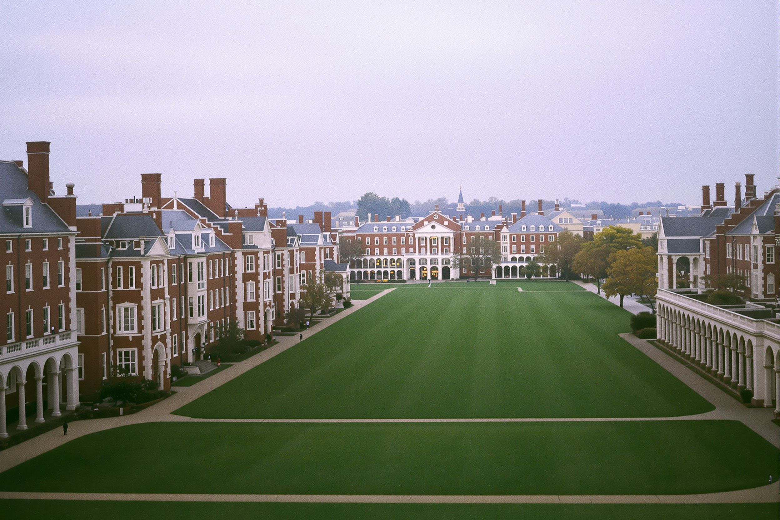 Red brick college buildings with colonnades around a long green lawn