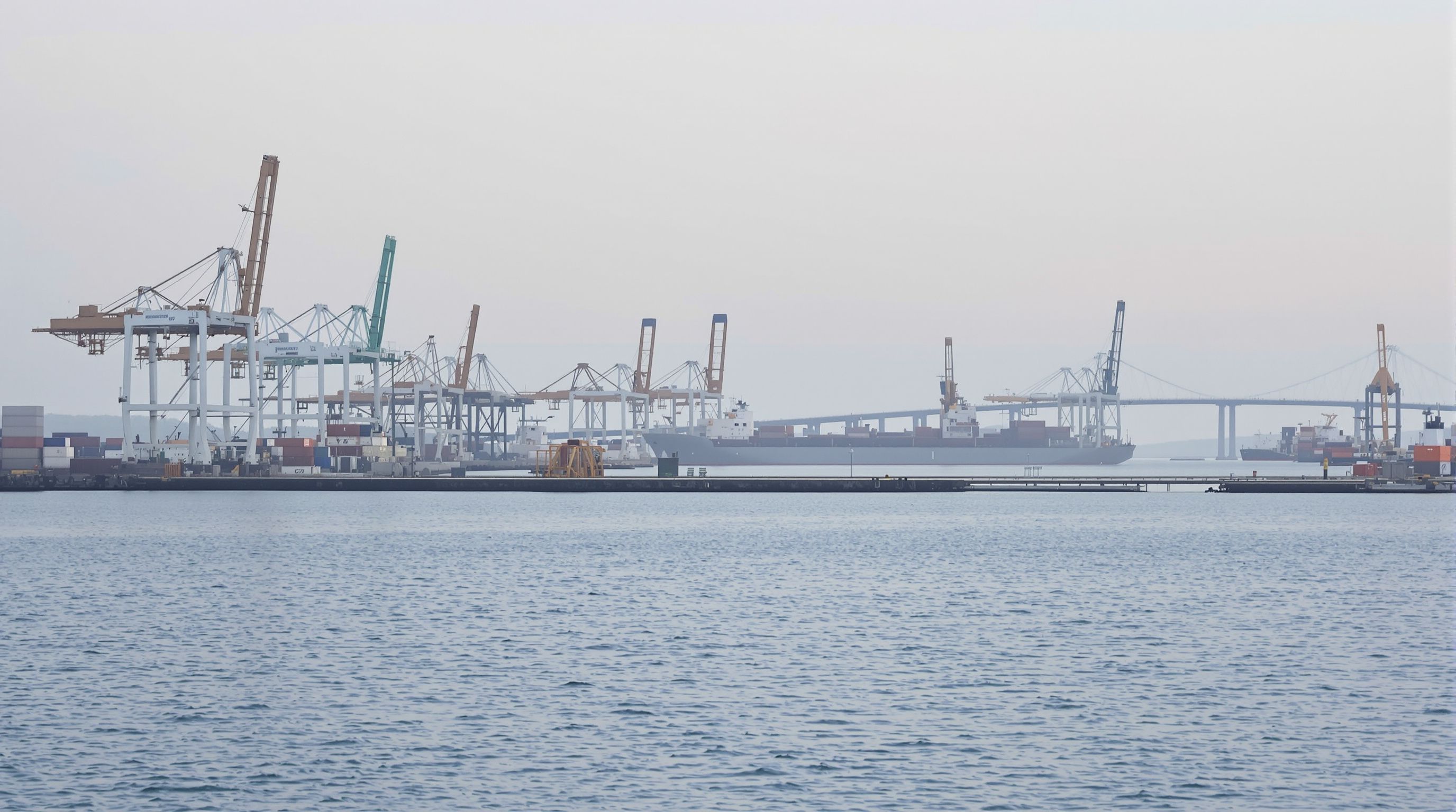 Container cranes and piers across a calm harbor at first light